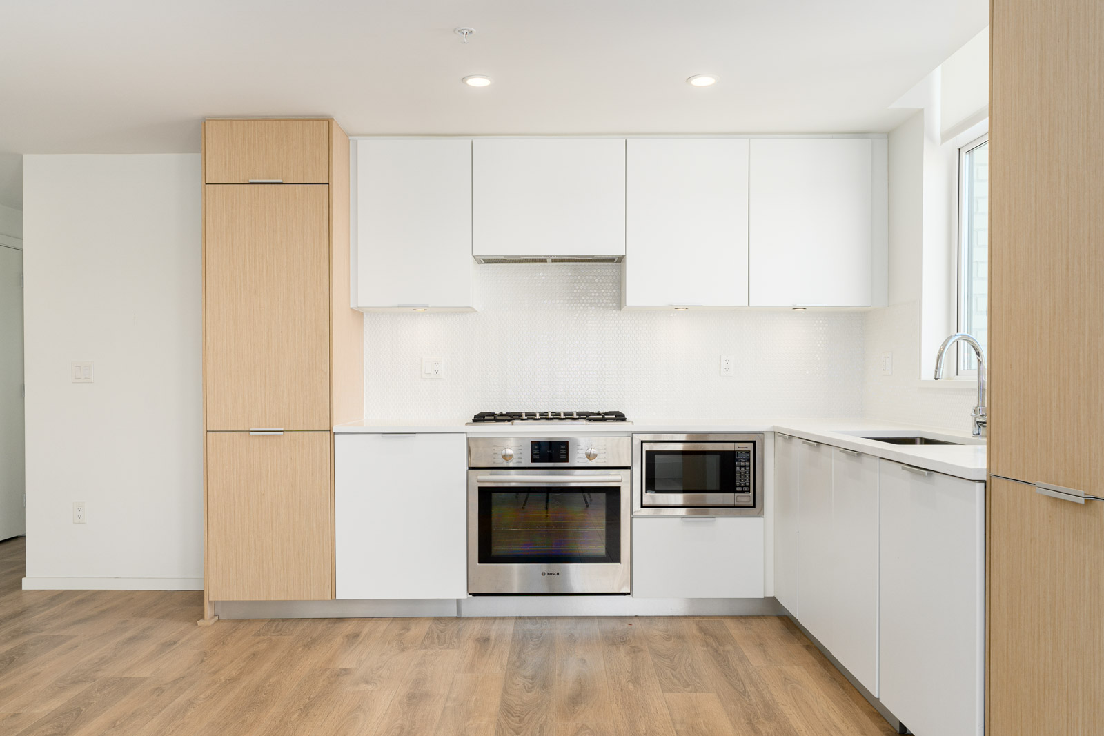 kitchen with stainless appliances, white cabinets, hardwood floors