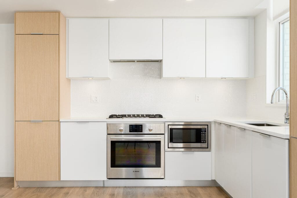 kitchen with stainless appliances, white cabinets, hardwood floors