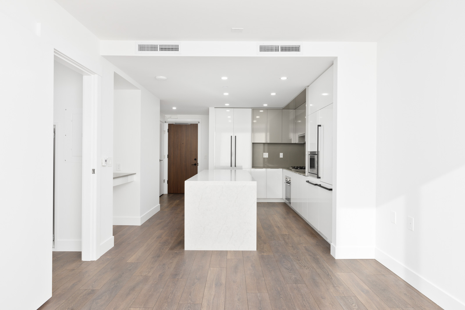 view of white kitchen, kitchen island and brown front door