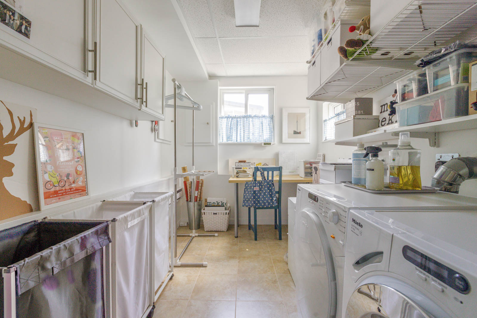 laundry room with Miele washer and dryer. Shelving above washer and dryer and cabinets across.