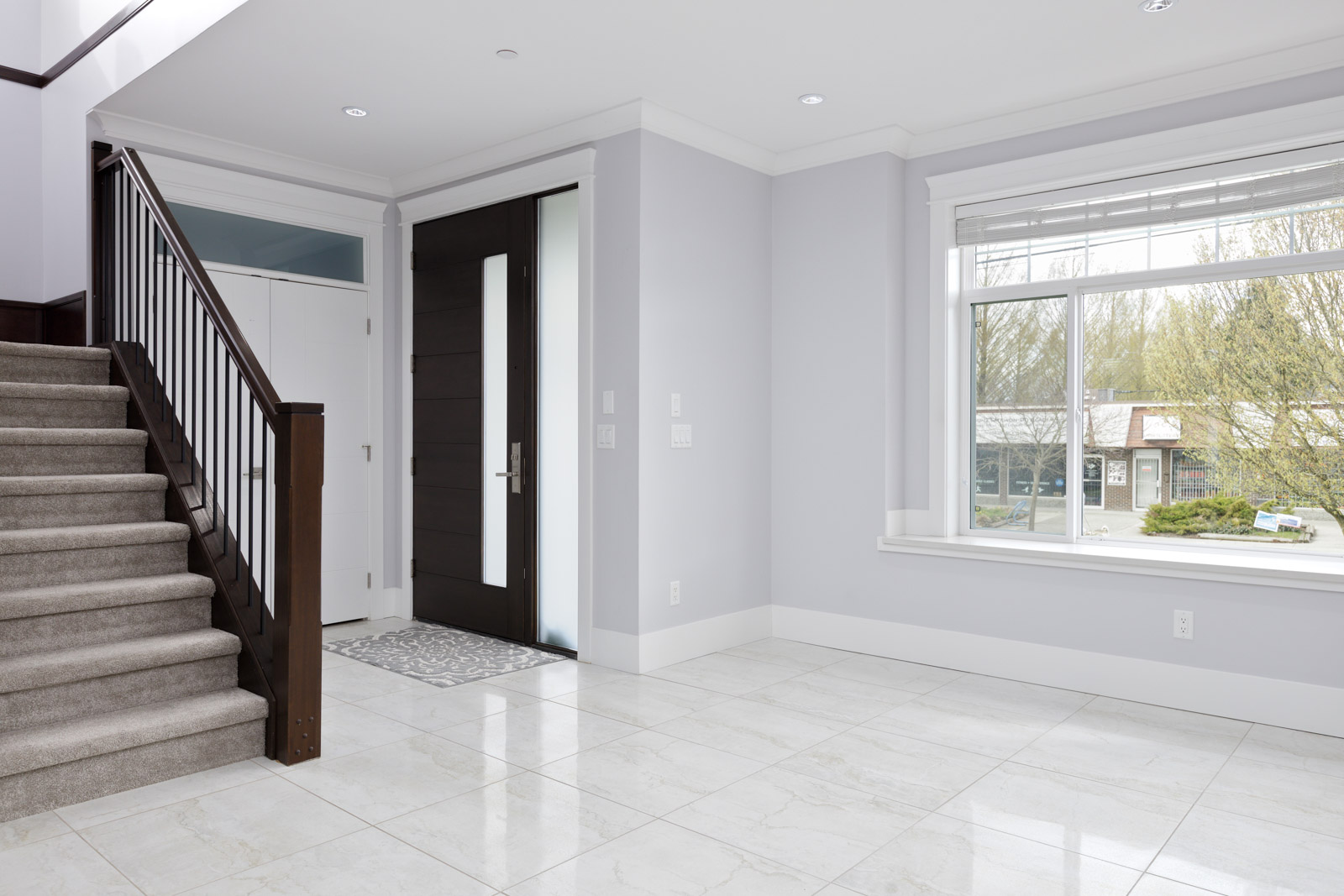 front entry way tiled with large windows and carpet stairs