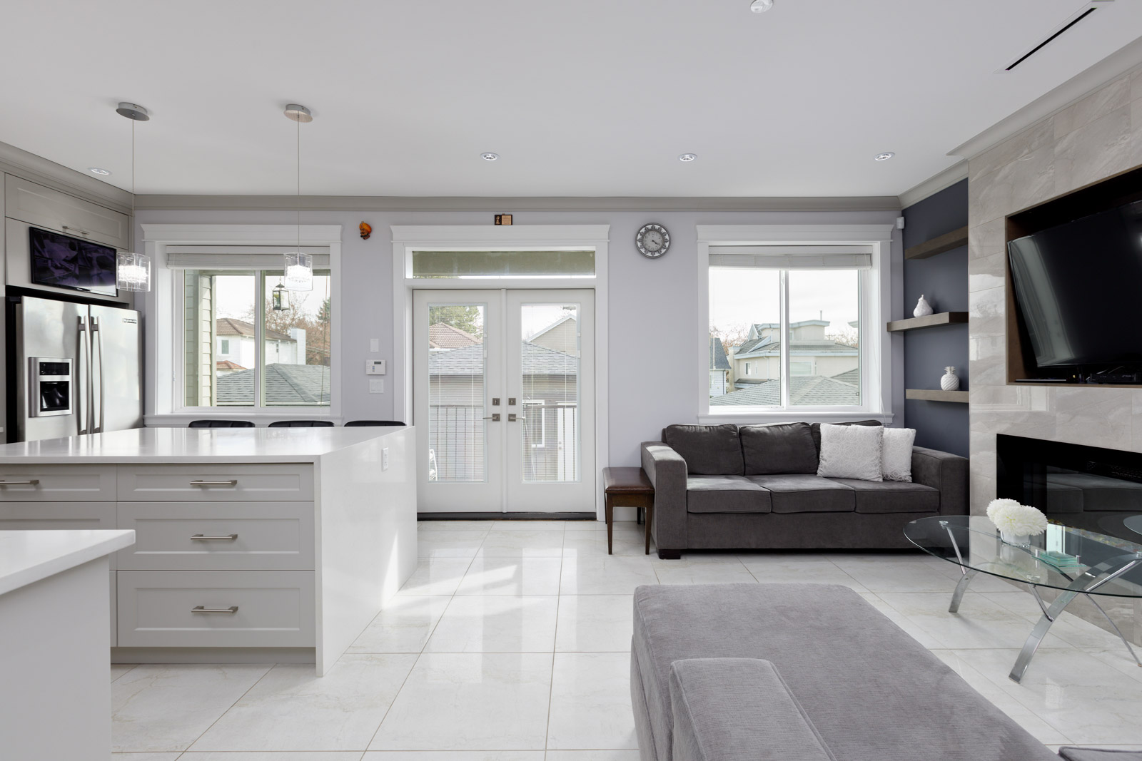large kitchen with view of double back doors leading to deck. couch and fireplace