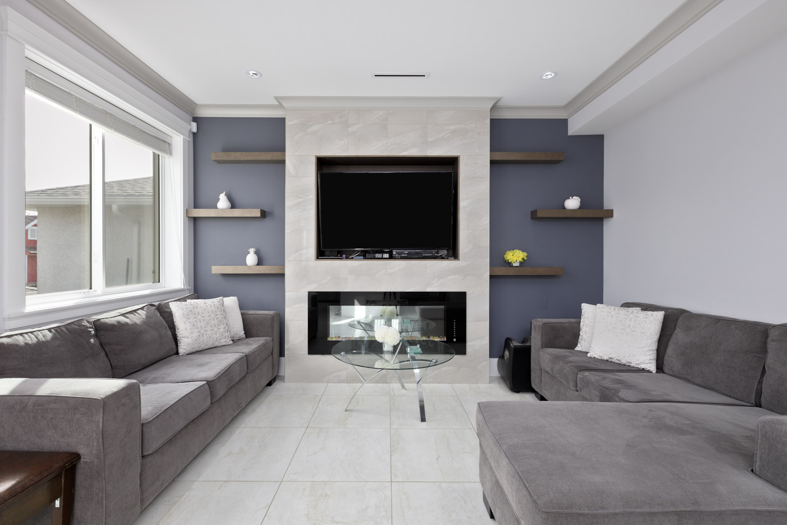 large living room with tiled floors, dark blue wall with fireplace in middle of wall.