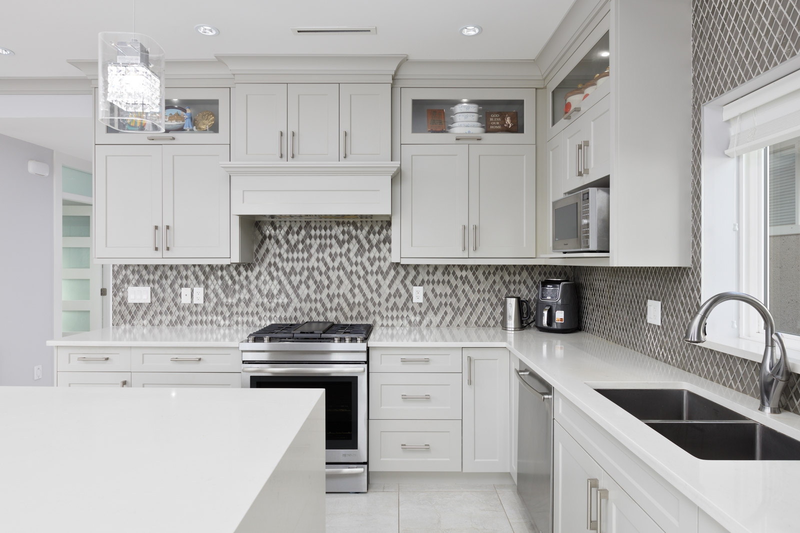 kitchen view of stove, microwave. All white counters with luxury feel