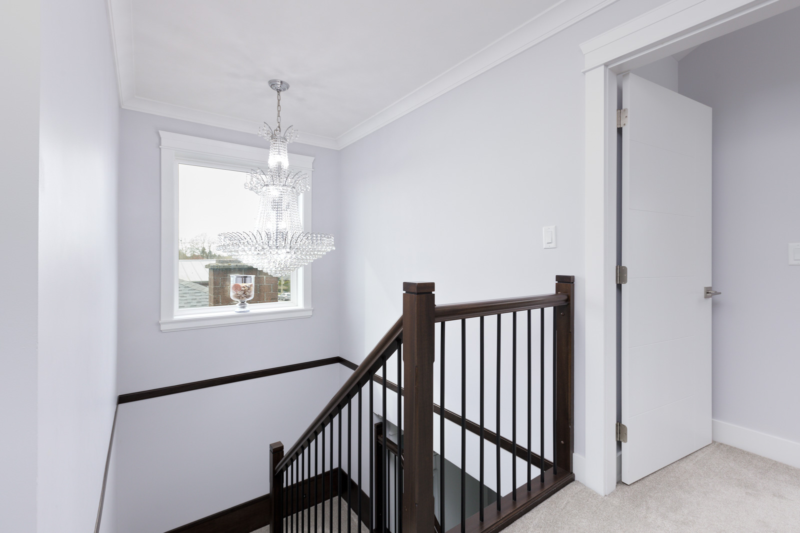 staircase with dark wood handrailing and large window and hanging chandelier