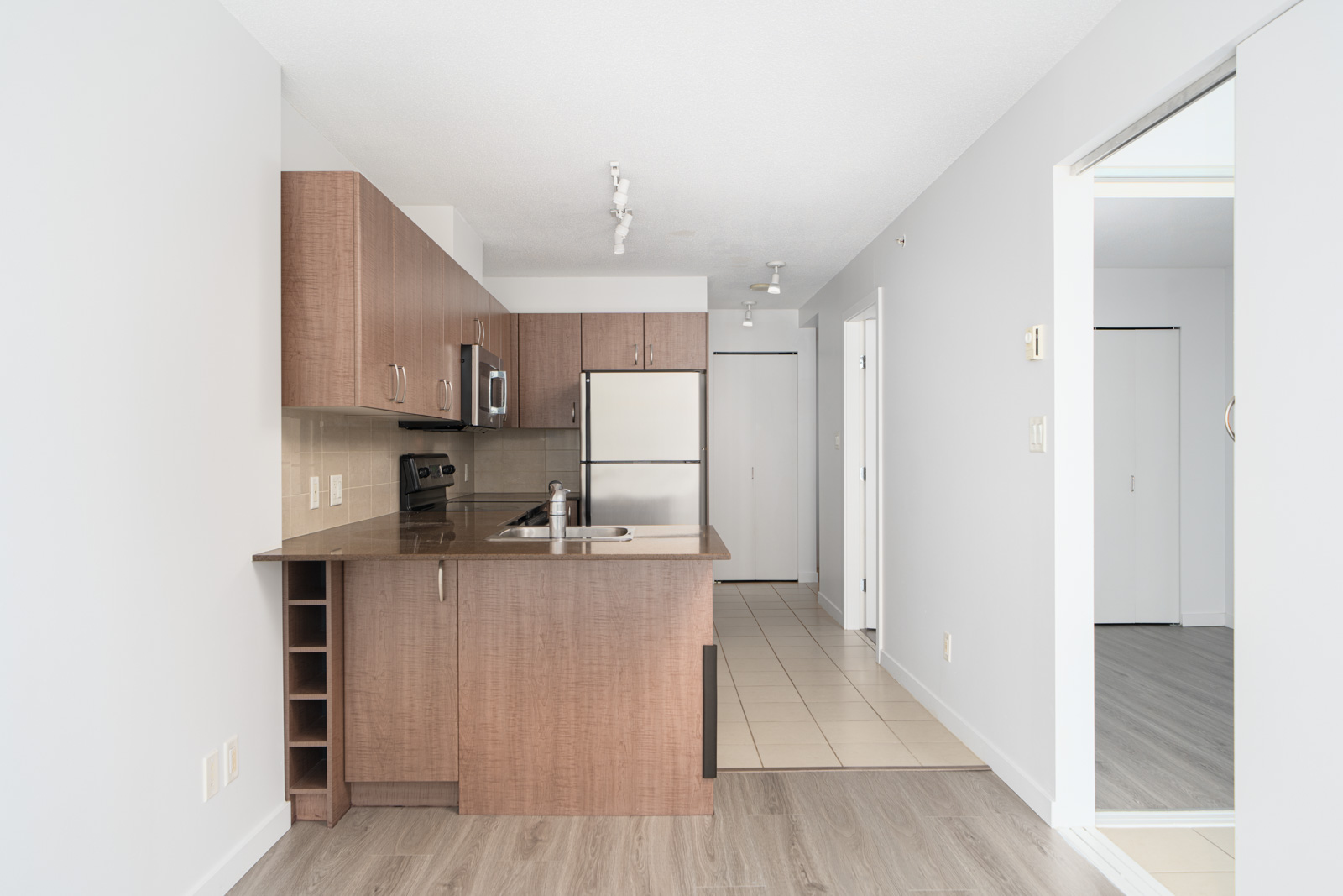 A modern kitchen with wooden cabinets, stainless steel appliances including an oven, microwave, and dishwasher, and a sink on the countertop.