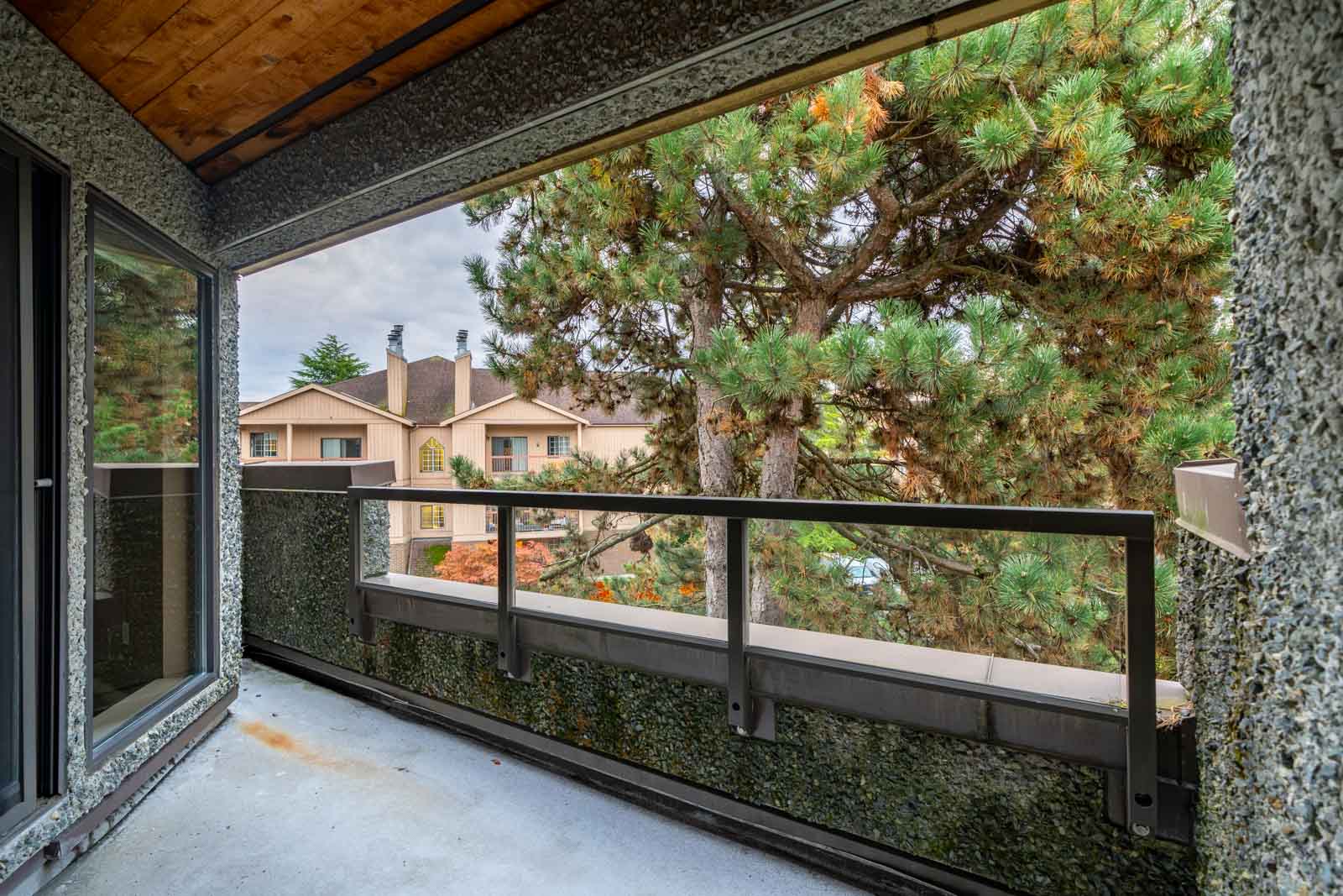 View from a balcony showing a tree and residential buildings with overcast sky.