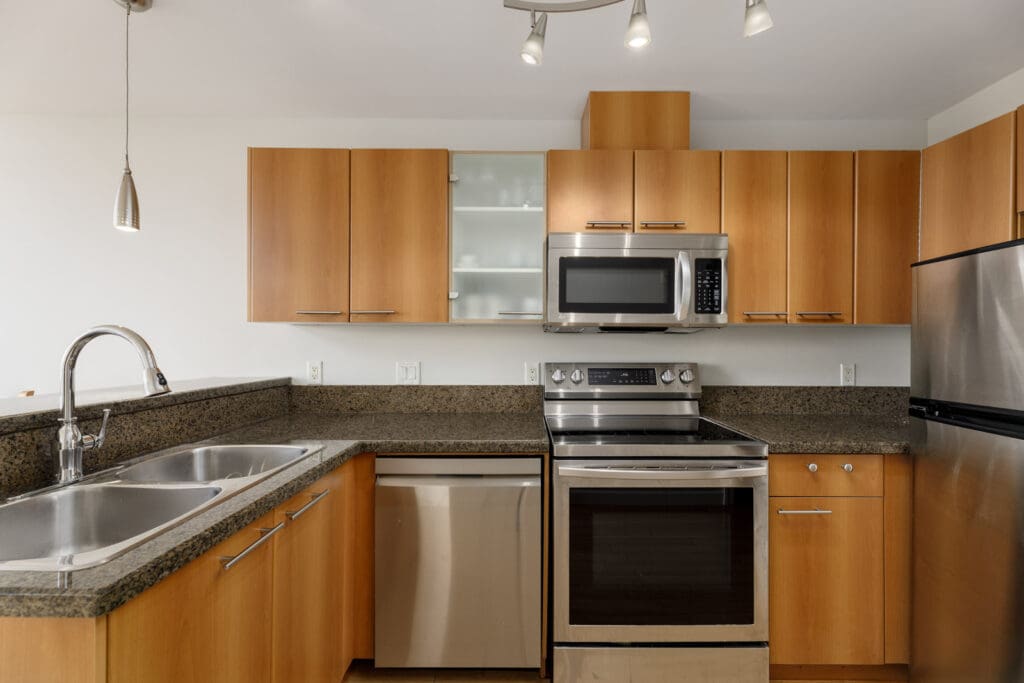 Modern kitchen with wooden cabinets, stainless steel appliances, double sink, and granite countertops.