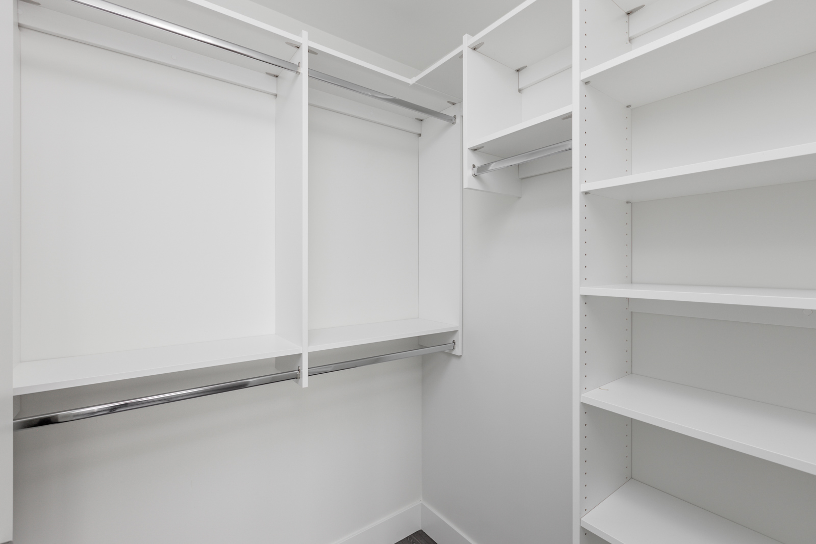 Empty white walk-in closet with shelves and hanging rods.