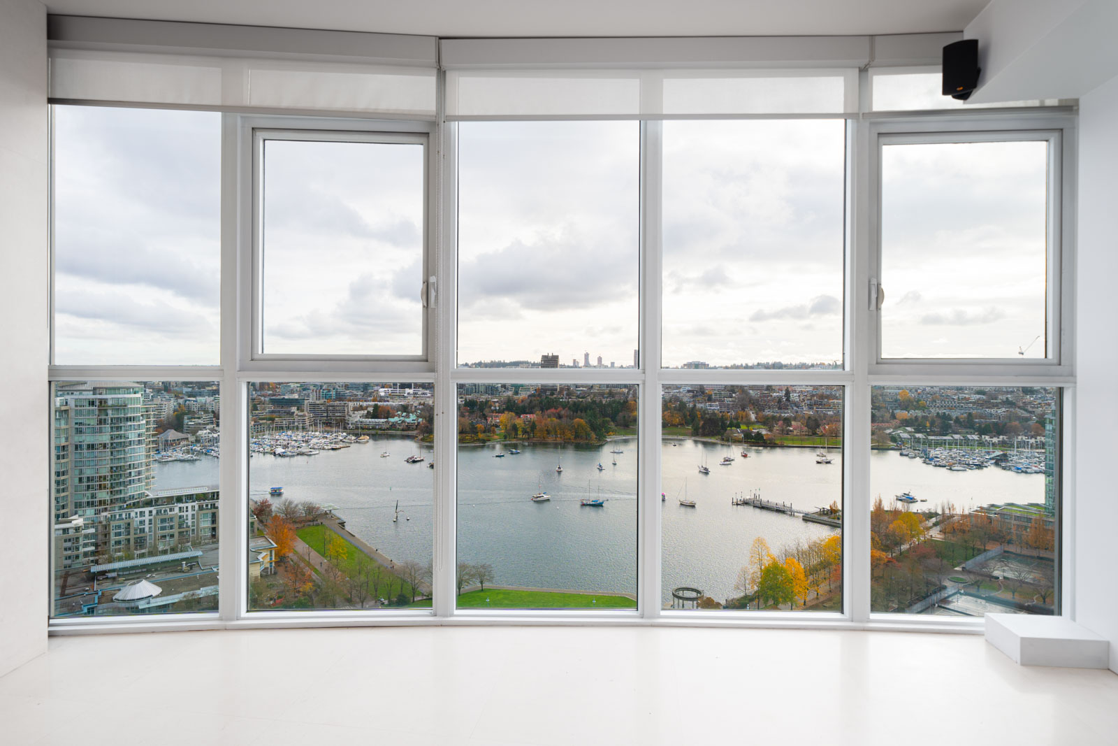 View from a large window overlooking a river, with boats and cityscape in the background under a cloudy sky.
