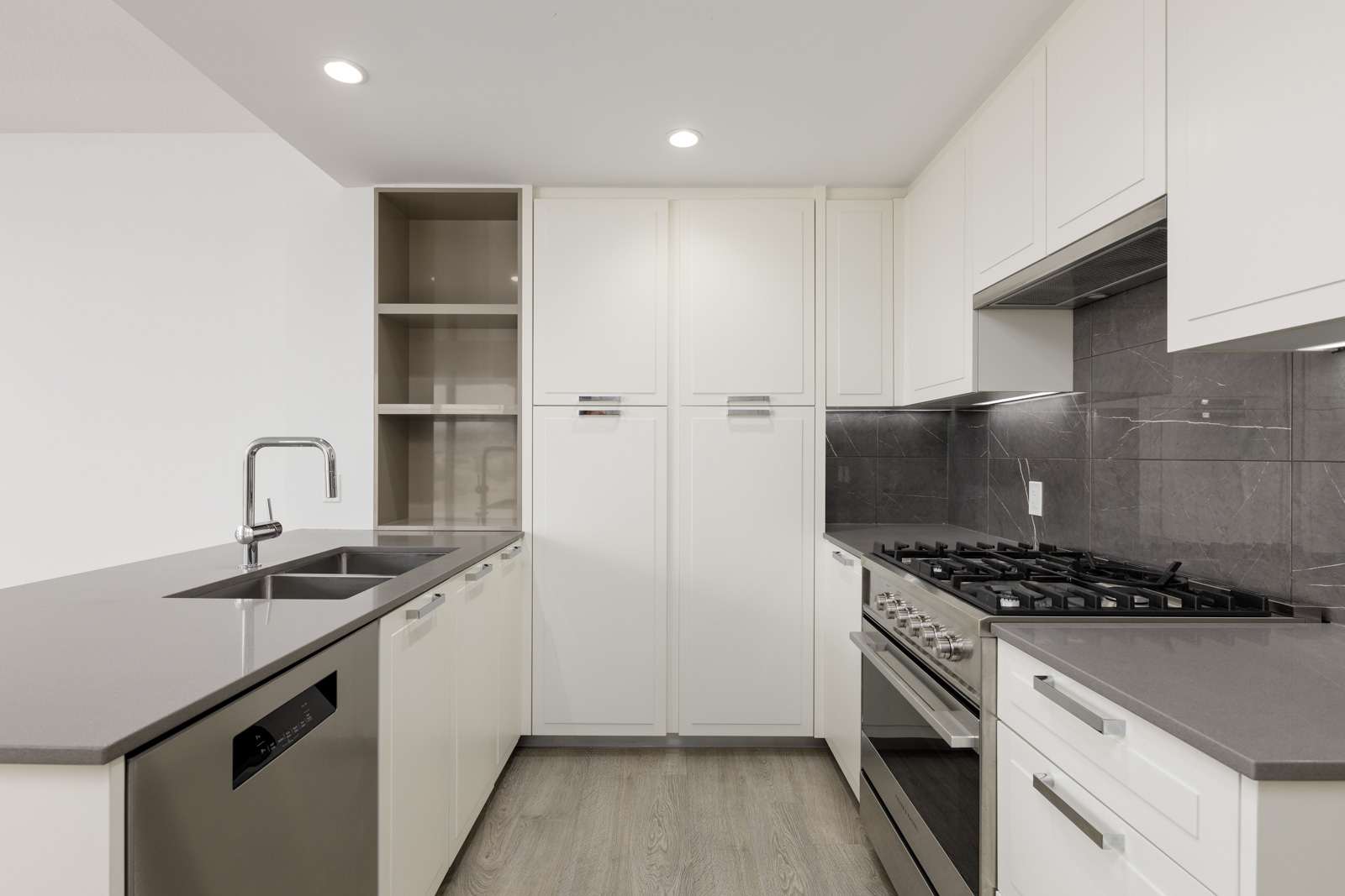 Modern kitchen with white cabinets, grey countertops, a stainless steel stove, dishwasher, and double sink.