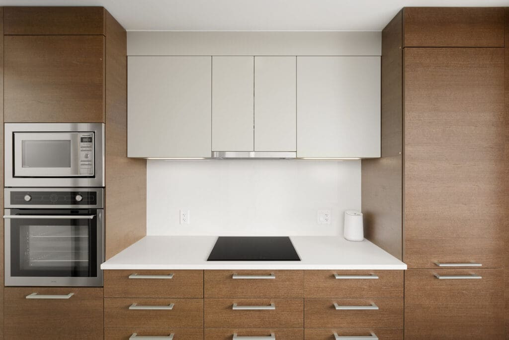 Modern kitchen with wooden cabinets, a built-in oven, a microwave, and an electric cooktop on a white countertop.