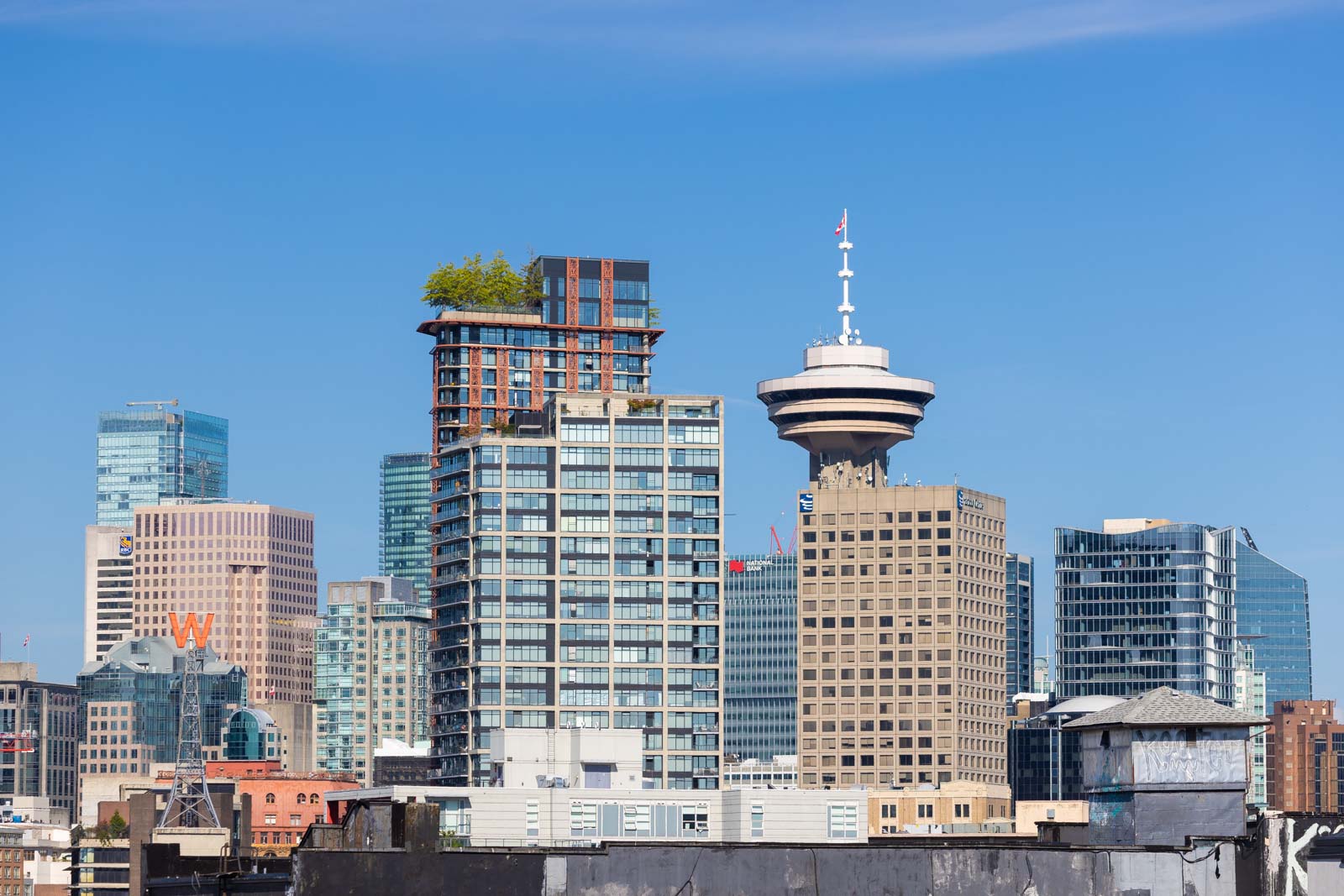 Vancouver skyline featuring modern skyscrapers and the distinctive Vancouver Lookout tower under a clear blue sky.